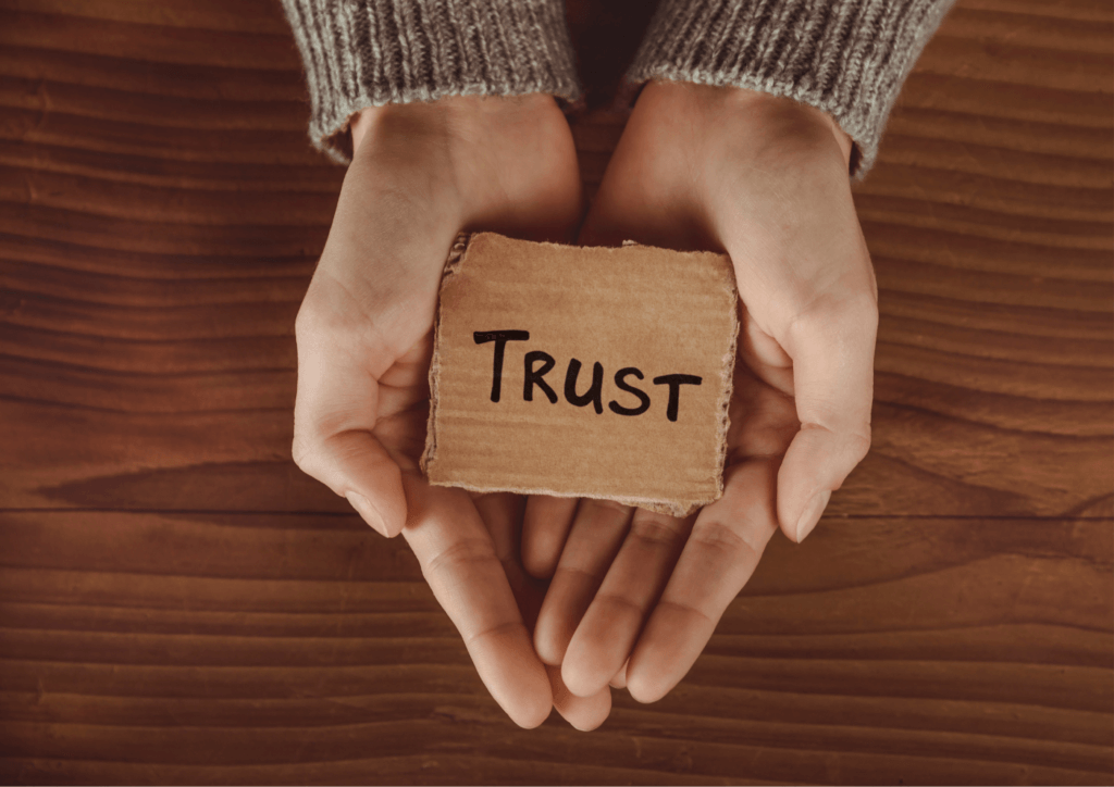 a person holding a piece of cardboard with a word trust on it