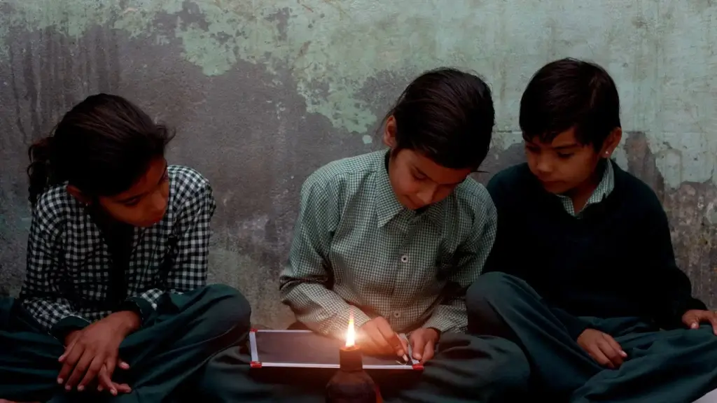 a group of children studying in candle light